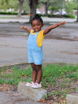A preschool-age black child stands with their arms outstretched